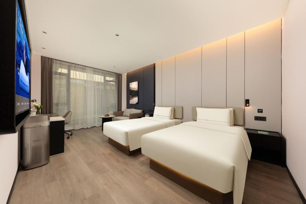 Atour Hotel Wujiaochang QuyangBailian ShoppingMall Shanghai في شانغهاي: غرفة فندق بها سريران وتلفزيون بشاشة مسطحة