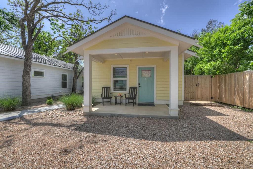ein kleines gelbes Haus mit einem Tisch und Stühlen in der Unterkunft The Grove Combo in Fredericksburg
