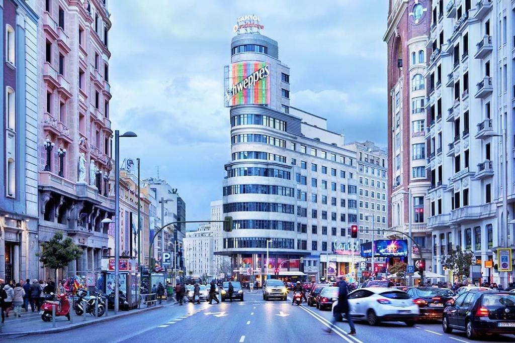 a busy city street with a tall building at Rooms in Madrid Downtown in Madrid