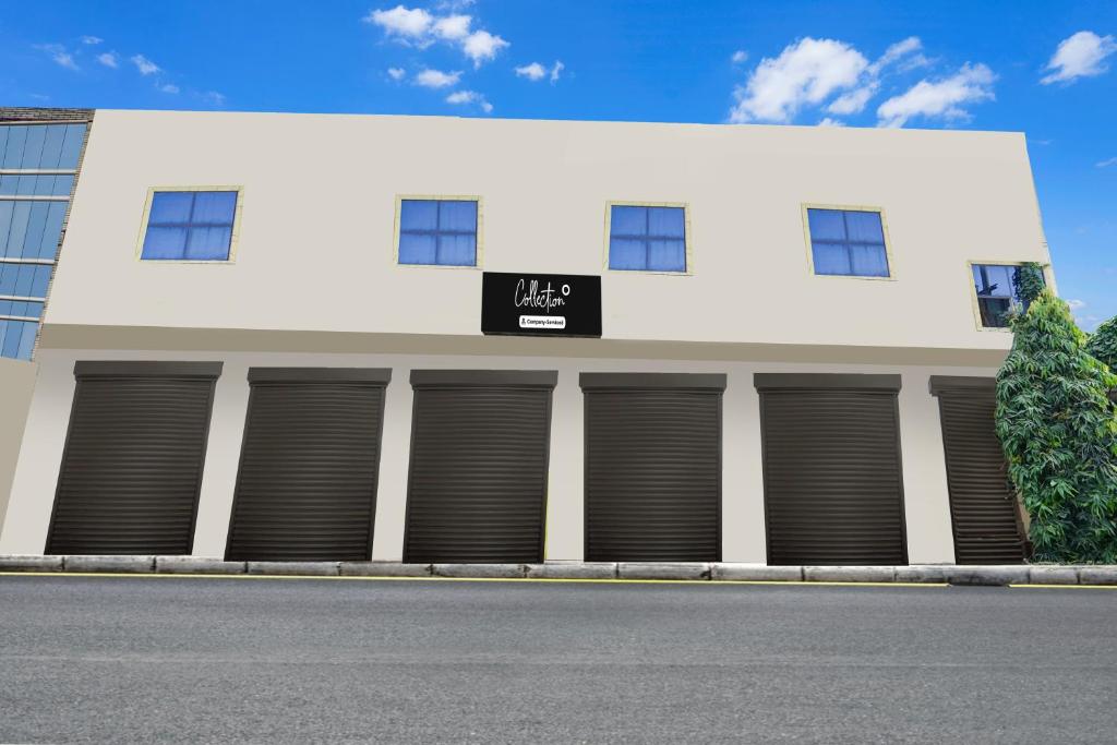 a white building with four garage doors on it at OYO Collection O Ratan Lal Nagar in Kānpur