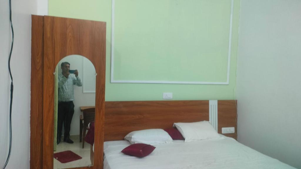 FaizābādにあるViram Homestaysの鏡のベッド写真を撮る女