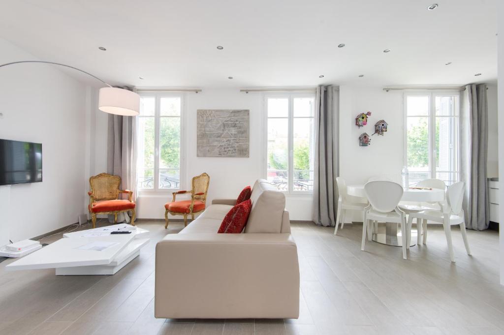 カンヌにあるAppartement design proche Croisette, classé 4 étoilesの白いリビングルーム(白いソファ、椅子付)