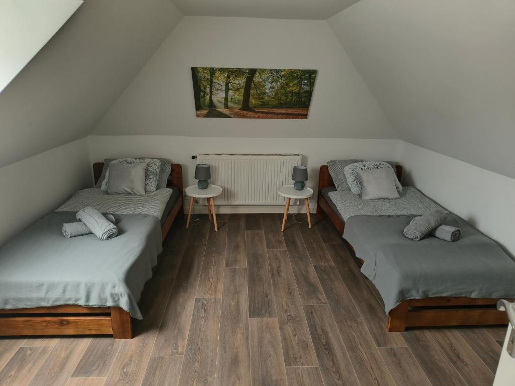 a attic room with two beds and two tables at Panoráma Vendégház Jásd in Jásd