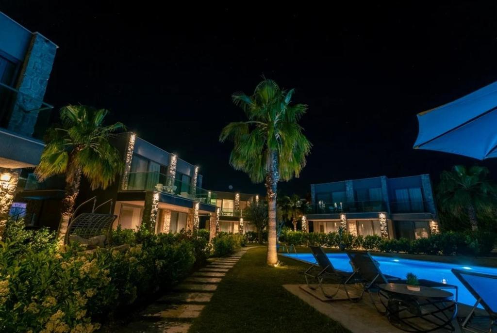 a resort with palm trees and a swimming pool at night at ares yalıkavak in Bodrum City