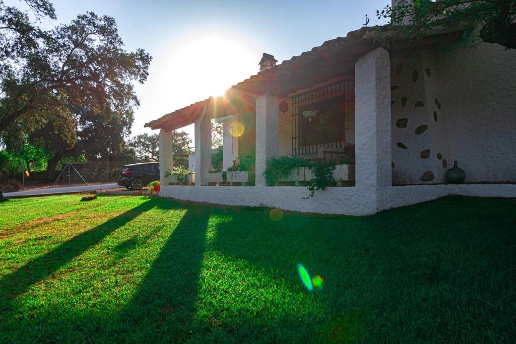 a house with the sun shining on the grass at Edomus Castillo de las Guardas in Seville