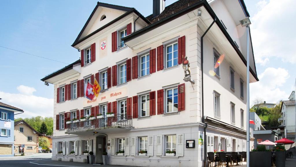 a large white building with red shuttered windows at Gasthof zum Mohren in Willisau