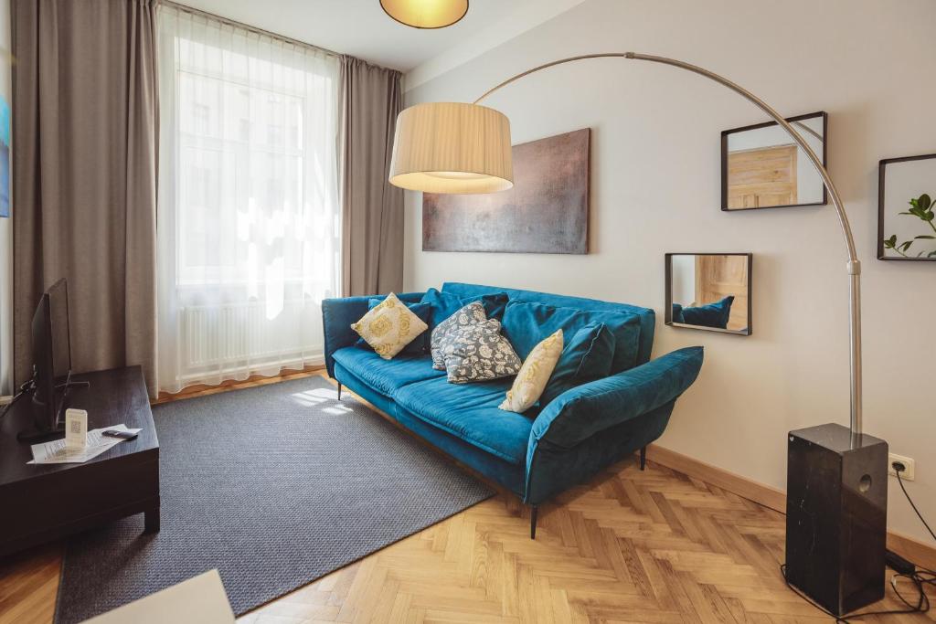 een woonkamer met een blauwe bank en een lamp bij Bearsleys Archers Apartments in Rīga