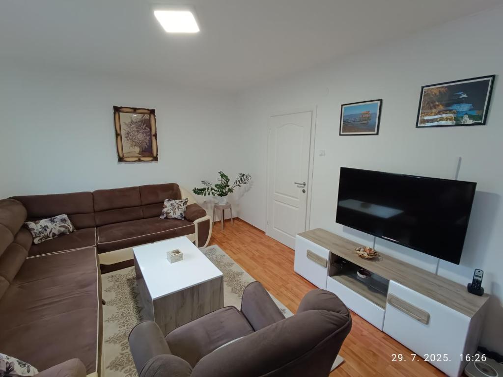 Una sala de estar con un sofá y un televisor de pantalla plana. en Apartman Orhideja, en Višegrad