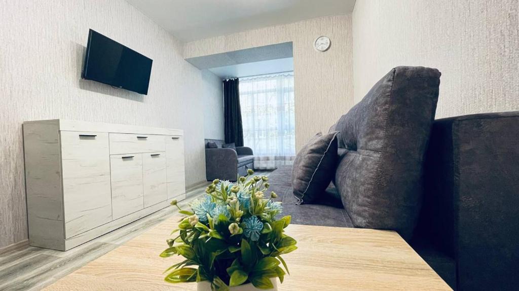 una sala de estar con sofá y un jarrón de flores en new apartment near the center квартира в новому будинку поруч з центром, en Sumy