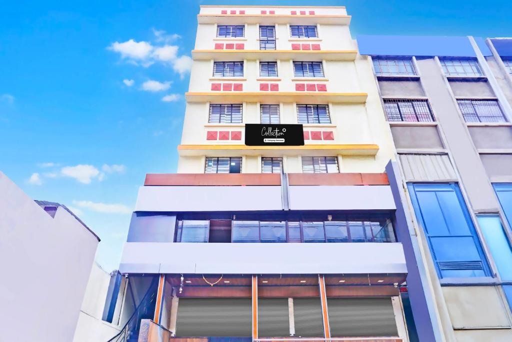 a tall white building with a sign on it at Super Collection O Katraj Near KK Market in Pune