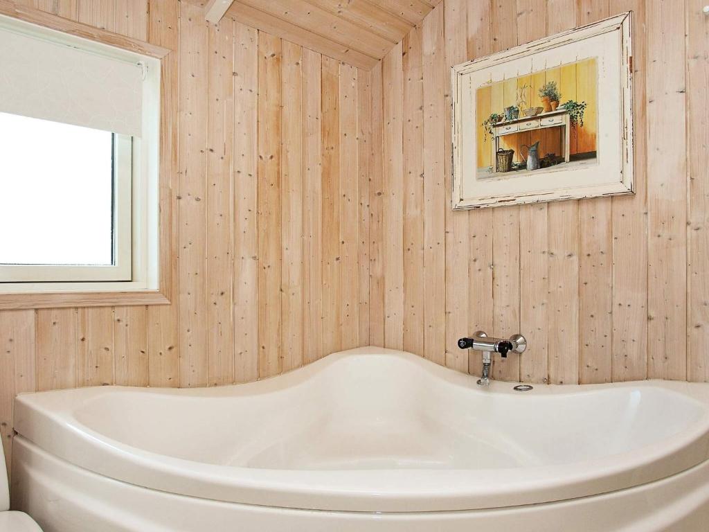 a white bath tub in a bathroom with a mirror at Modern Beach Retreat - By Traum Ferienwohnungen in Løkken