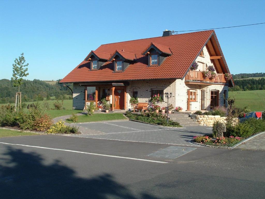 a house with a red roof on a road at Gästehaus Jüngling in Kottenborn