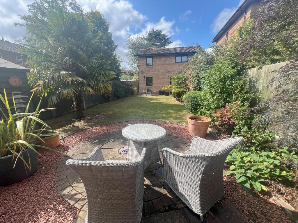 a patio with a table and chairs in a yard at Superb Comfy 2 Bed House, Responsive & Caring Hosts Free WiFi & Parking, Close to MK Centre, Train Station, Santander, Network Rail by Webbhill Stays in Milton Keynes