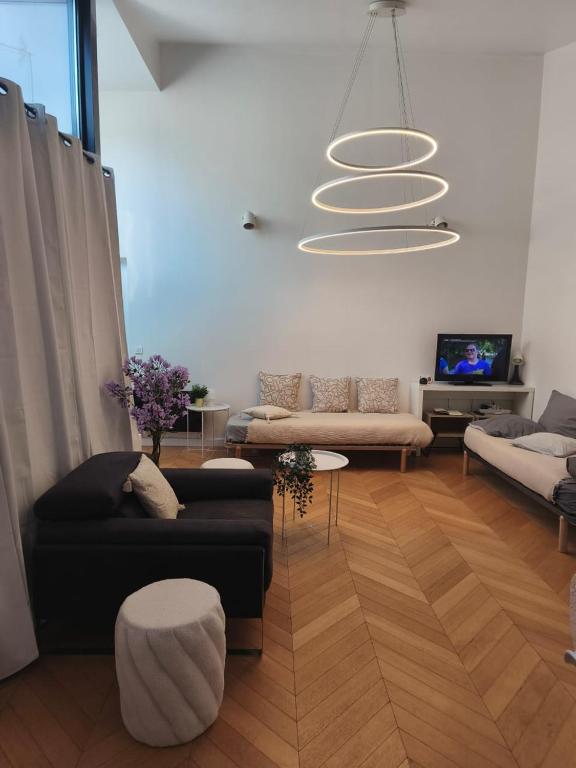 サン・モール・デ・フォッセにあるCosy F2 à Saint Maur des Fossésのリビングルーム(ブラックソファ、シャンデリア付)