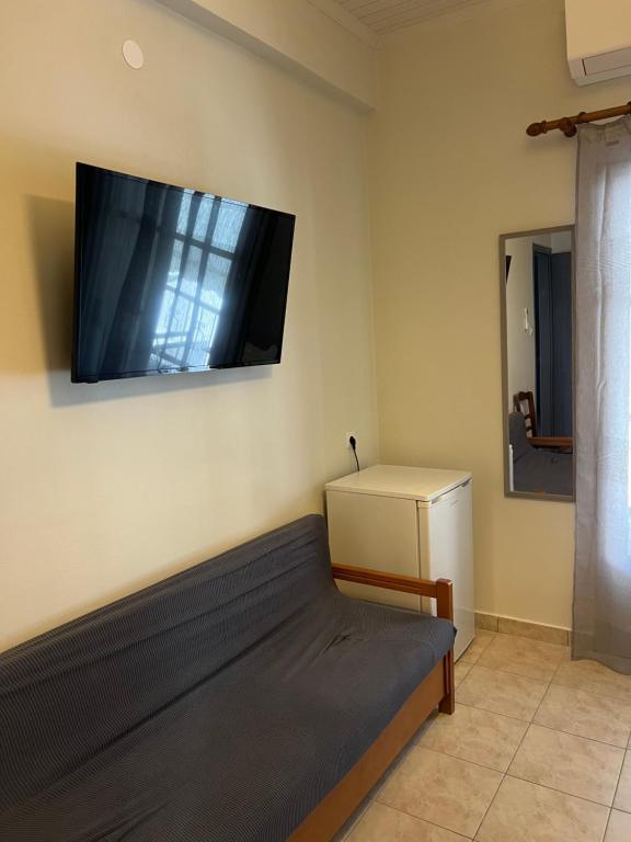 a room with a bed and a flat screen tv on the wall at Kanarinia Guesthouse in Kala Nera