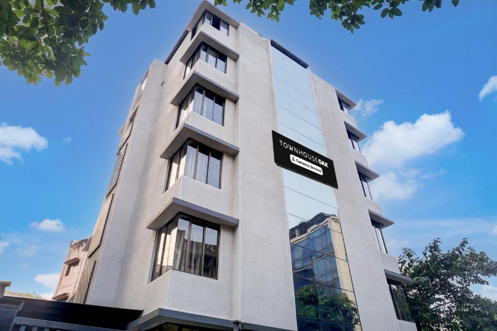 a tall white building with a sign on it at Super Townhouse Oak Viman Nagar Formerly Kuber Inn in Pune
