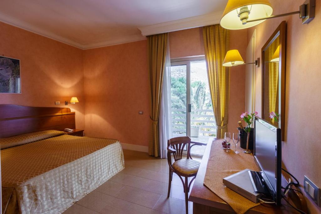 a hotel room with a bed and a desk with a television at Hotel Conchiglia d'Oro in Mondello