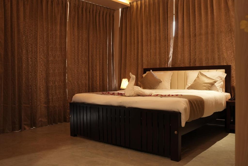 a bedroom with a large bed with white sheets at Woods N Wilds in Virajpet