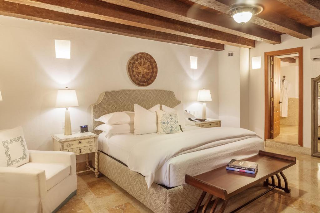 a bedroom with a bed, a dresser and a lamp at Hotel Casa San Agustin in Cartagena de Indias