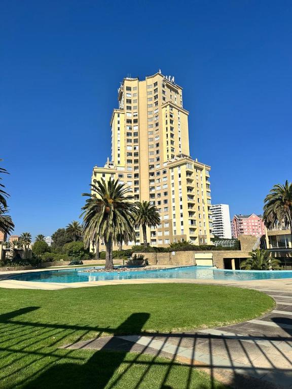 a large building in the background with a lawn and a building at Departamento Full Equipado in Concón