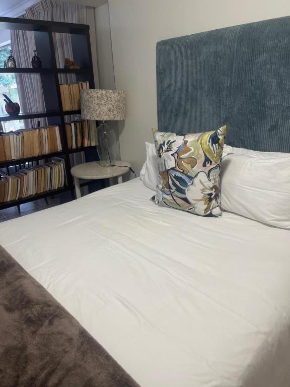 a white bed with a pillow and a book shelf at Broadway in Durban