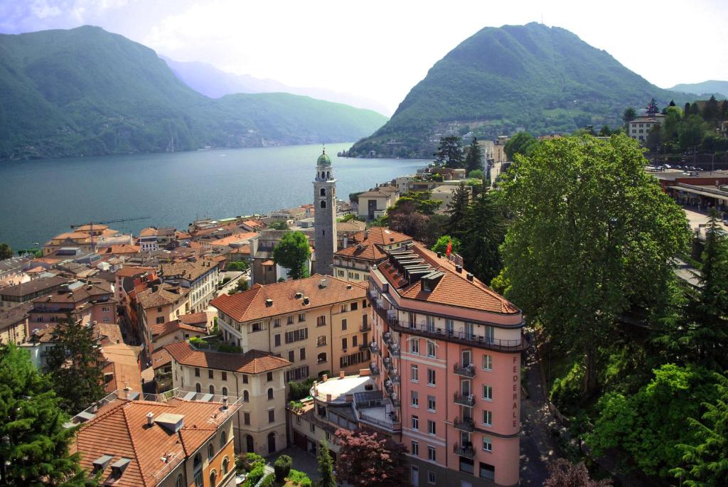 a view of a town with a lake and mountains at Hotel Federale in Lugano