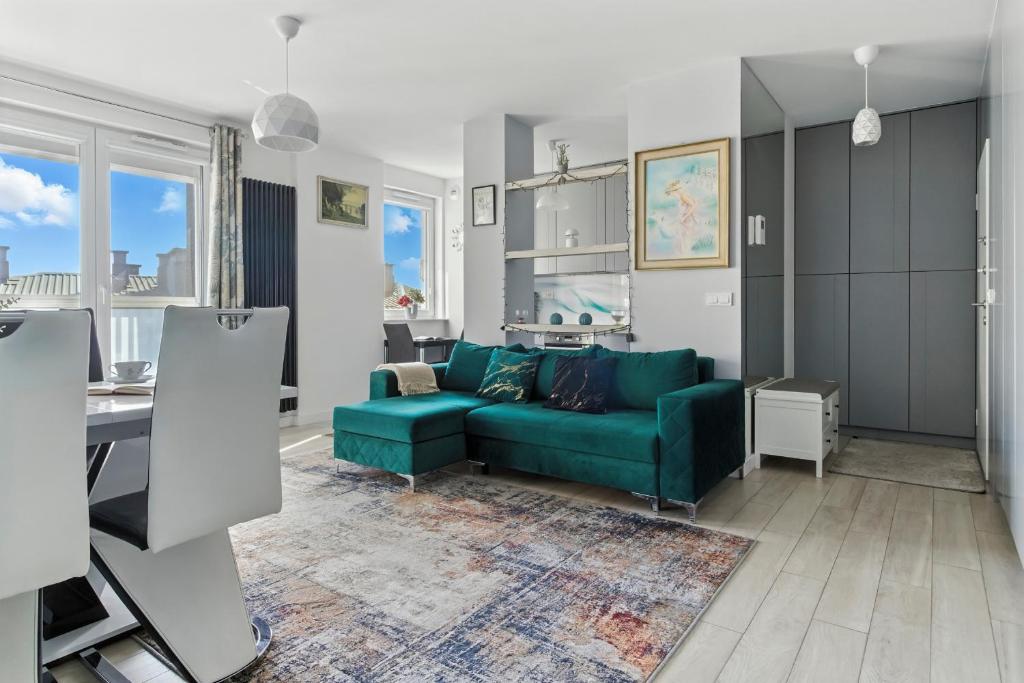 a living room with a green couch and a table at Pełczyńskiego Comfort Stay by Solarento in Warsaw