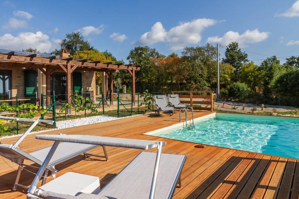 a pool on a wooden deck with chairs and a house at Agriturismo Ornelleta in Scansano