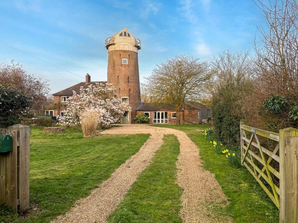 une maison avec une tour au sommet d'un chemin de terre dans l'établissement The Mill House, à Hindolveston
