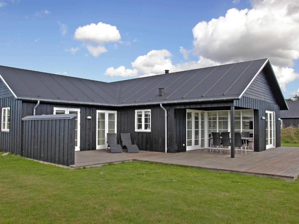 a house with a black roof and a deck at 8 person holiday home in Nysted in Nysted