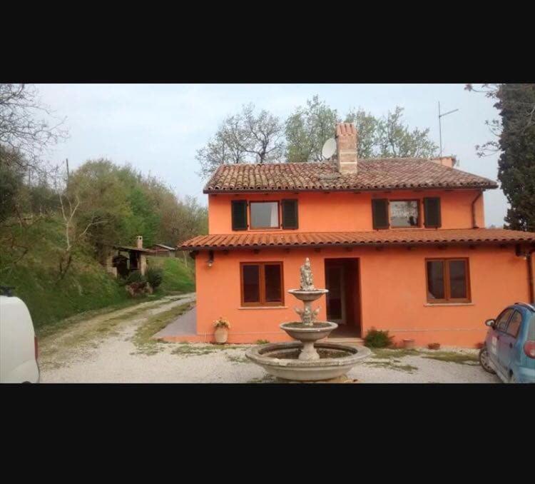 a small orange house with a fountain in front of it at Val migi in Montegaudio