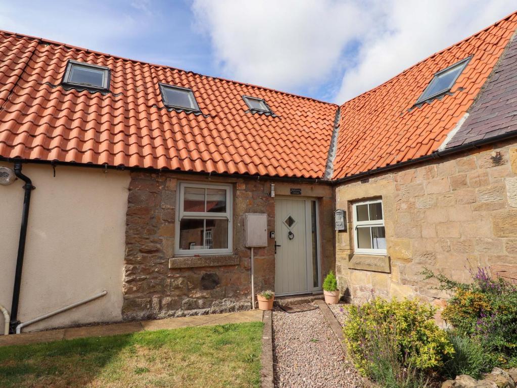 an old stone house with an orange roof at Barleycorn Cottage in Belford