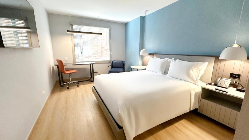 a hotel room with a large white bed and a desk at Hotel Habitel Select in Bogotá