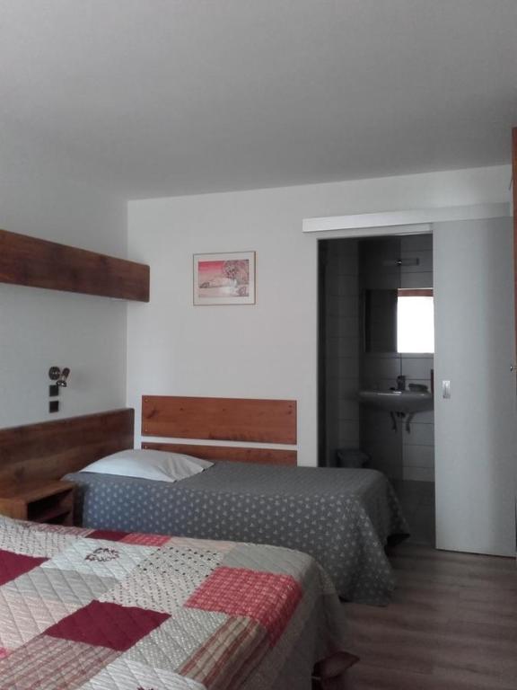 1 dormitorio con 2 camas y baño con lavamanos en Hotel Du Jura en Audincourt