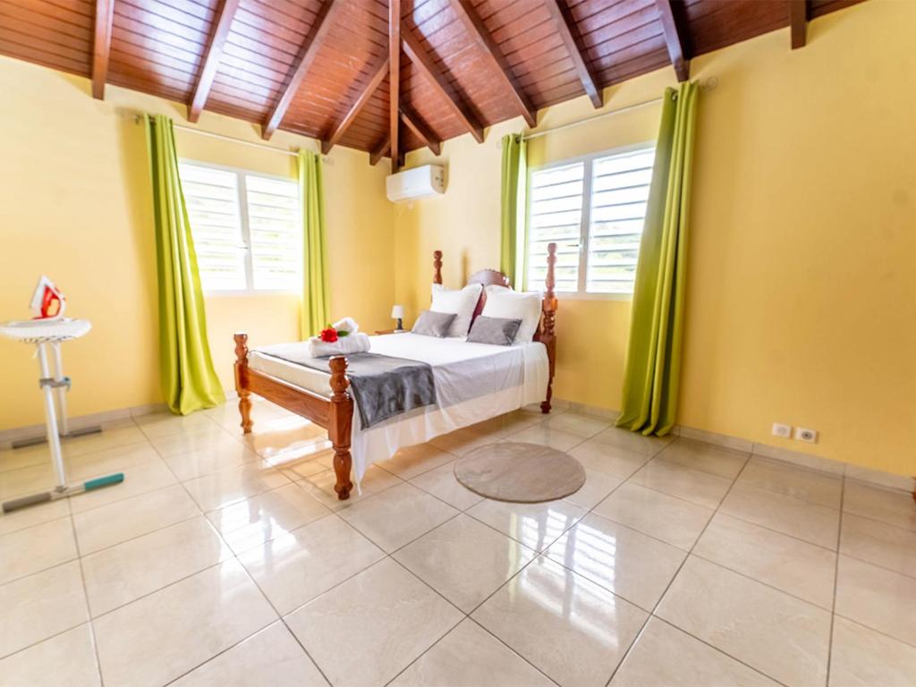 a bedroom with a bed and two windows at Logement Solèy Rivyè- 3 chambres in Petit-Bourg