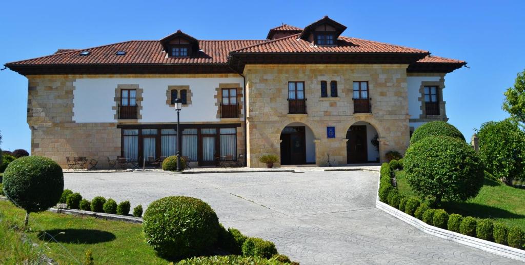a large stone house with a red roof at Hotel Valle De Arco in Prellezo