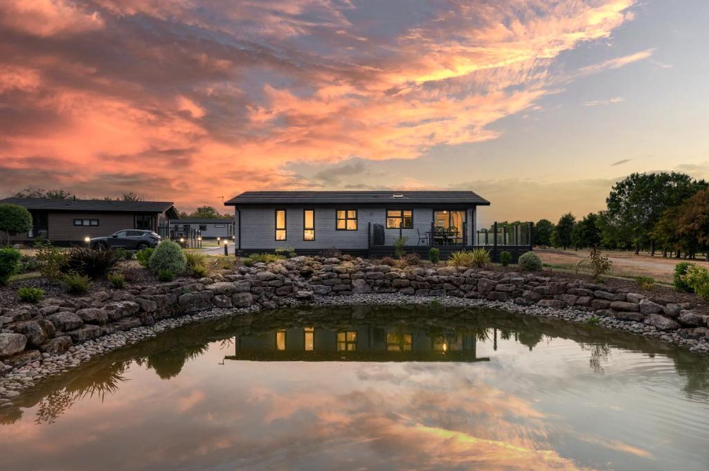 una casa con un estanque delante de ella en Finest Retreats - Cambridge Luxury Lodge, 