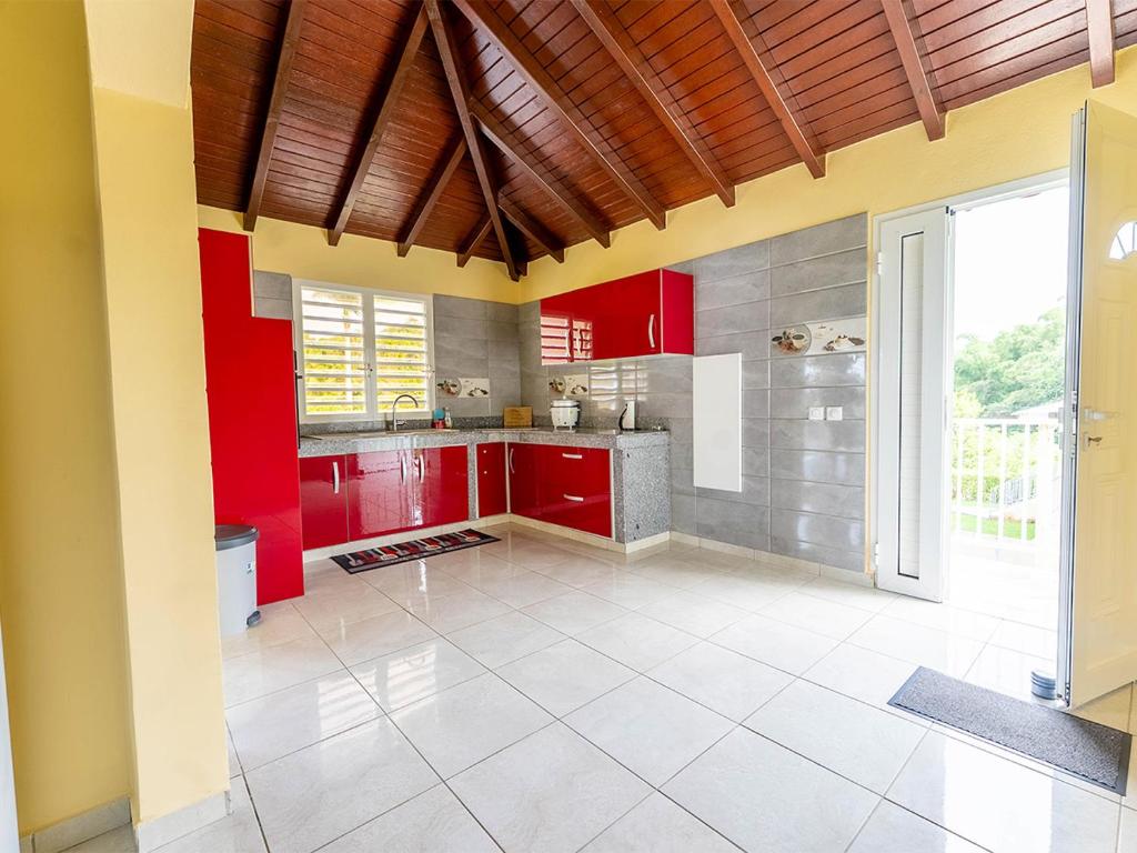 a kitchen with red cabinets and a large window at Logement Solèy Rivyè- 3 chambres in Petit-Bourg