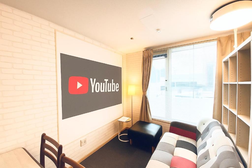 a room with a couch and a sign on the wall at 優ハウス夢ハウス2階 in Furano