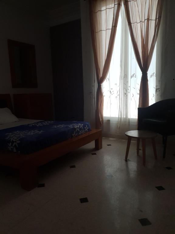a bedroom with a bed and a window with curtains at R flaurence la marsa in El Haouach