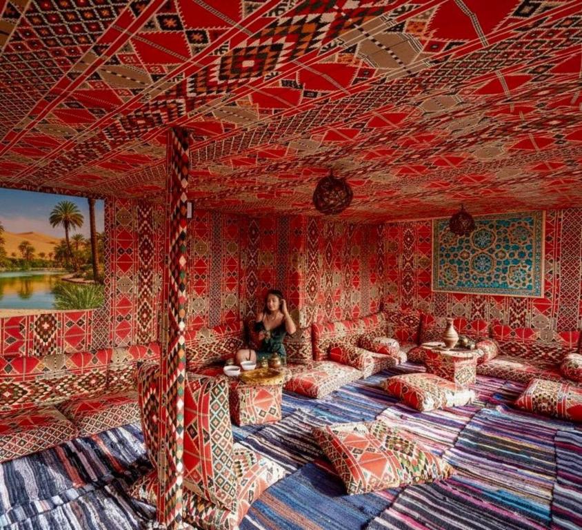 a woman is sitting in a room with two beds at Bedouin Camp pyramids view INN in Cairo