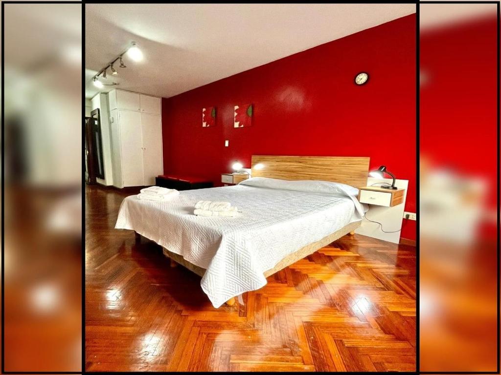 Un dormitorio con una cama grande con una pared roja. en Gran monoambiente en centro de Buenos Aires (1C), en Buenos Aires