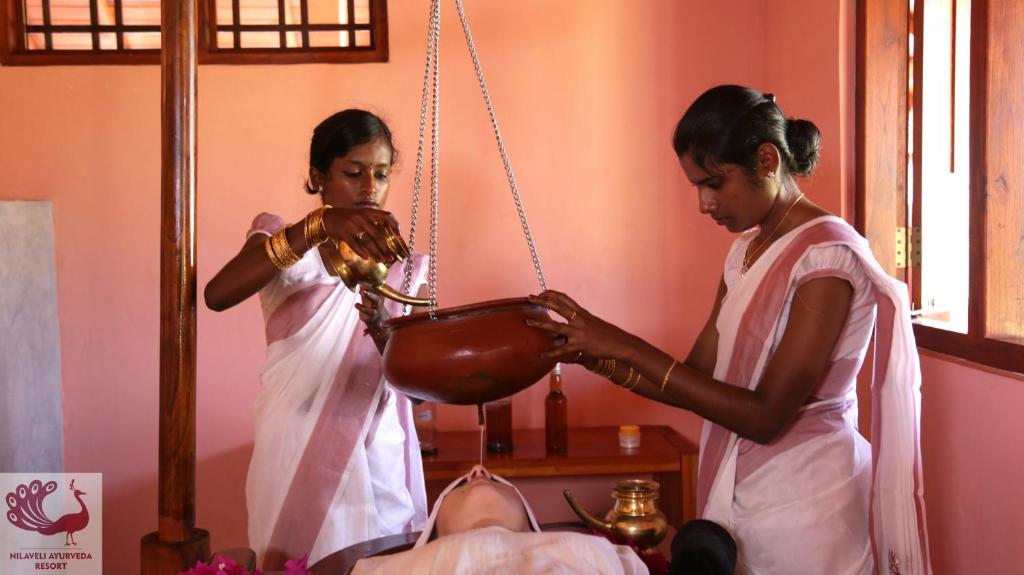 Deux femmes dans une pièce qui cuisine dans un bol dans l'établissement Nilaveli Ayurveda Resort, à Nilaveli