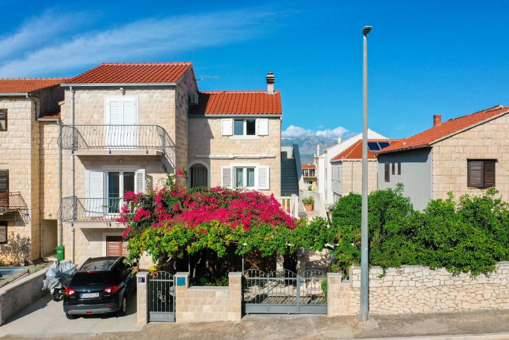 un'auto parcheggiata di fronte a una casa con fiori rosa di Apartment Vrba a Supetar (San Pietro di Brazza)