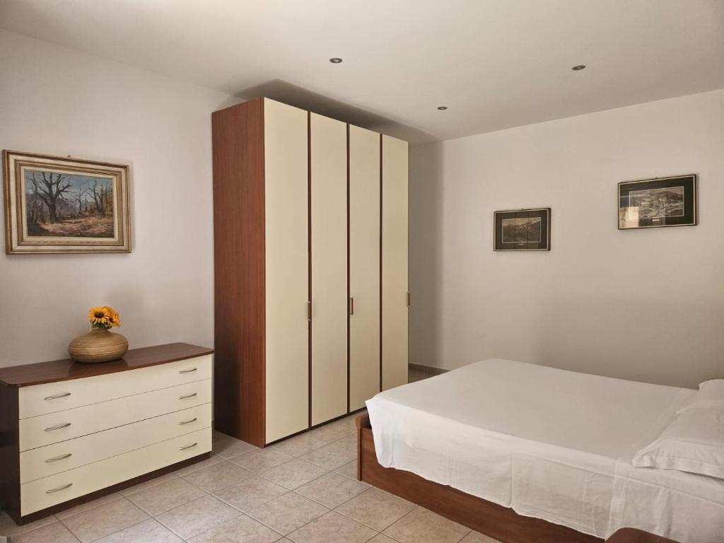 a bedroom with a white bed and a wooden cabinet at Casa Adelina - Appartamento Pallanza centro in Verbania