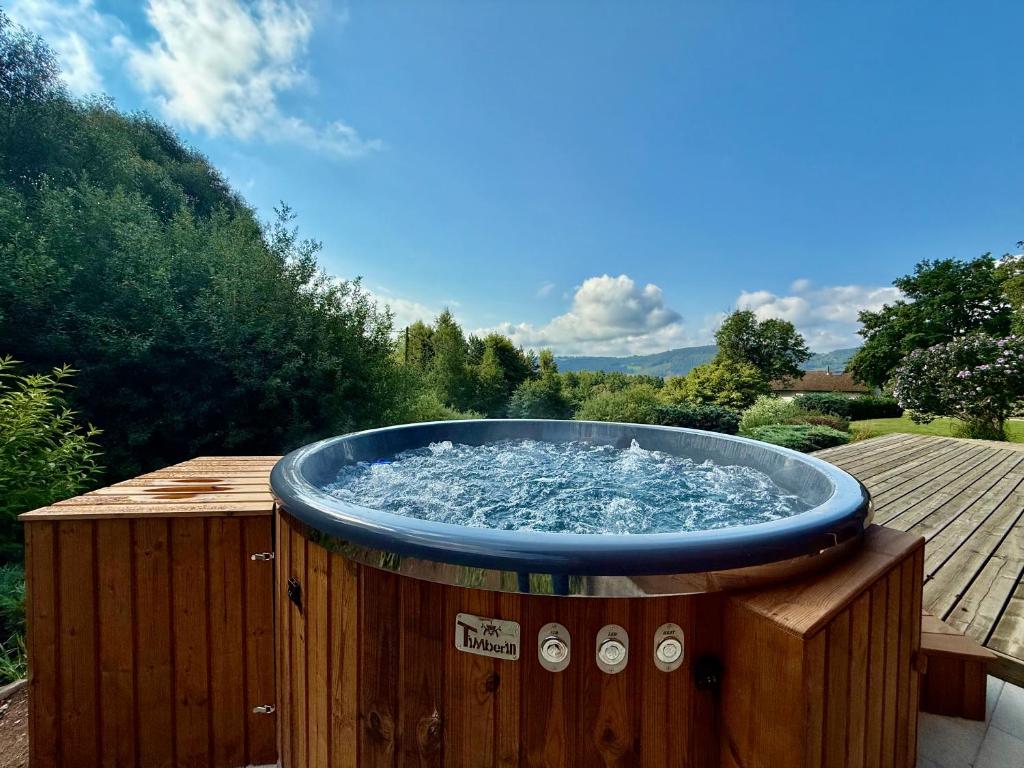 a hot tub filled with water on a wooden deck at Chalet Le Chappoix - SPA, terrasse et grand jardin in Granges-sur-Vologne