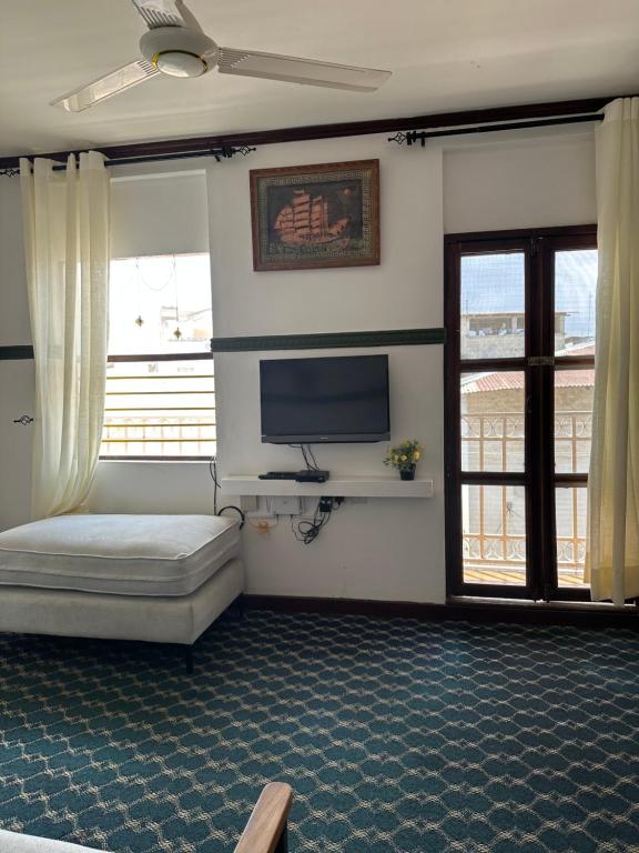 a room with a bed and a tv and windows at Home sweet house in Zanzibar City