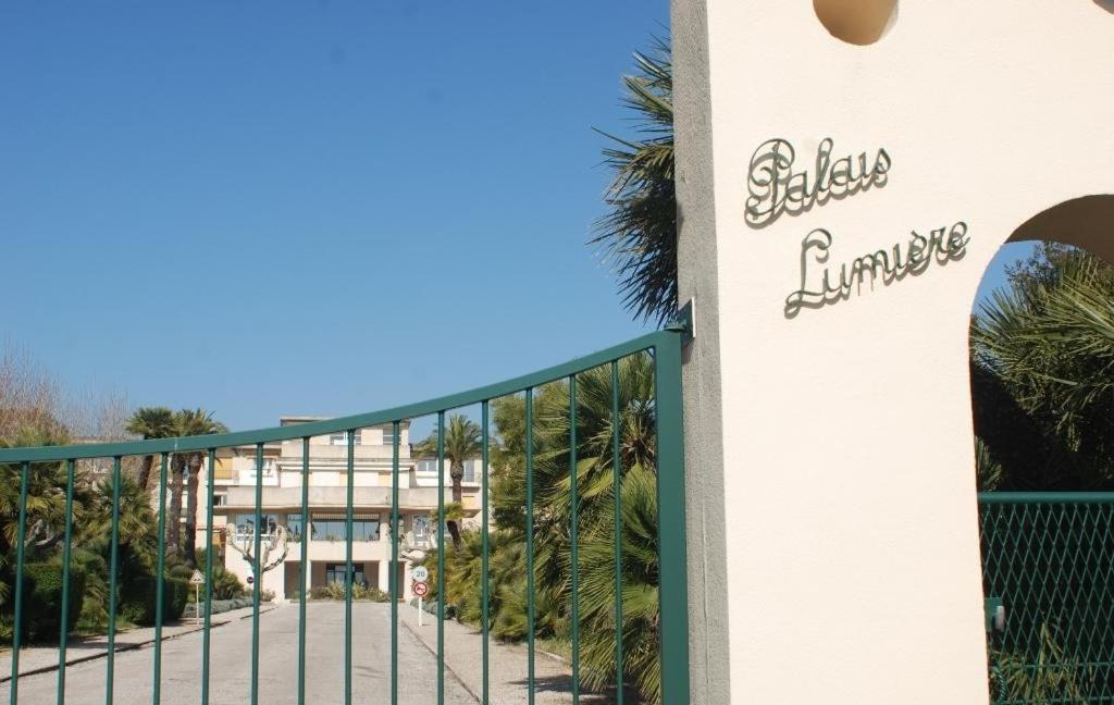 a gate in front of a building with palm trees at PALAIS LUMIERE : la ''Chambre Blanche'' in La Ciotat