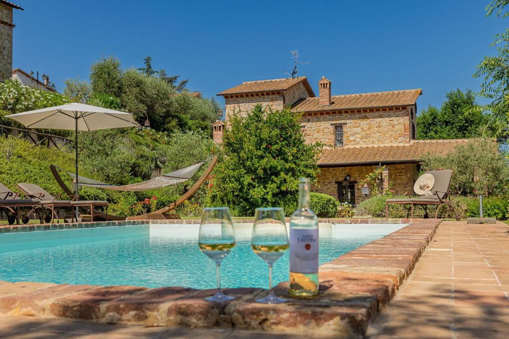 two glasses of wine sitting next to a swimming pool at Scappo in Umbria, casale della quiete in Montecchio