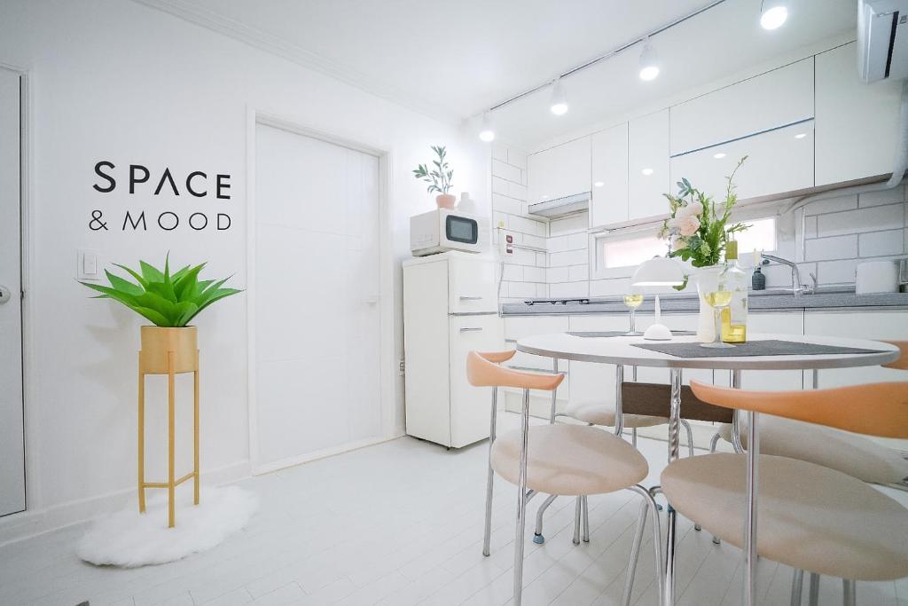 a white kitchen with a table and chairs at SPACE & MooD in Busan